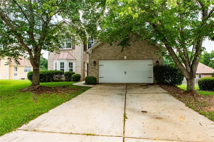 Brick exterior residence featuring a two-car garage with decorative hardware, a bay window with a copper-tone roof, and a concrete driveway