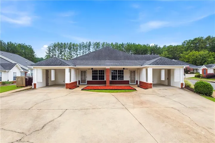 Duplex property with red brick accents, white siding, and a dark shingle roof