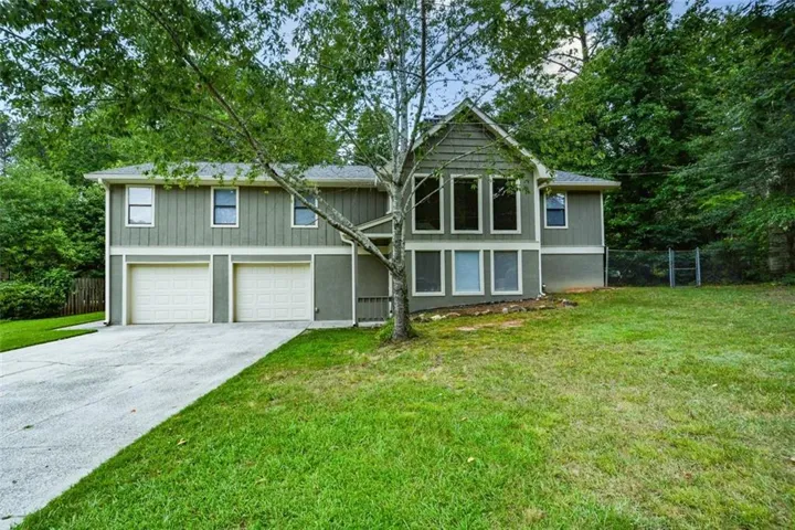 Split-level residence featuring a neutral exterior, multi-pane windows, and a two-car garage with individual doors