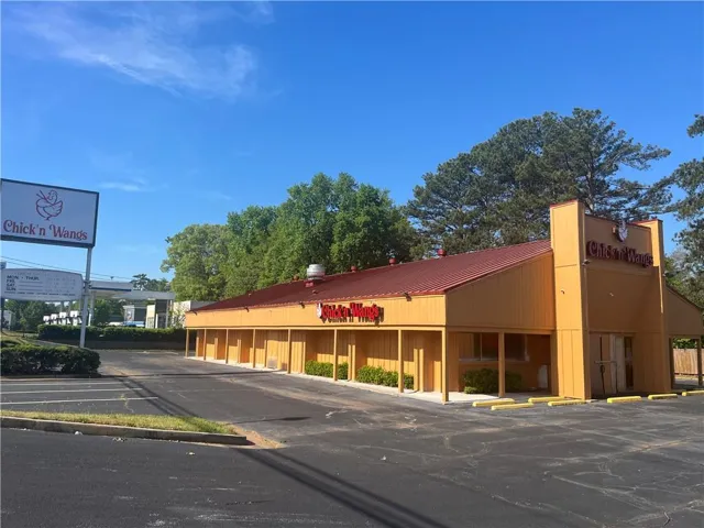 Commercial building with a red metal roof, yellow siding, and a prominent freestanding sign