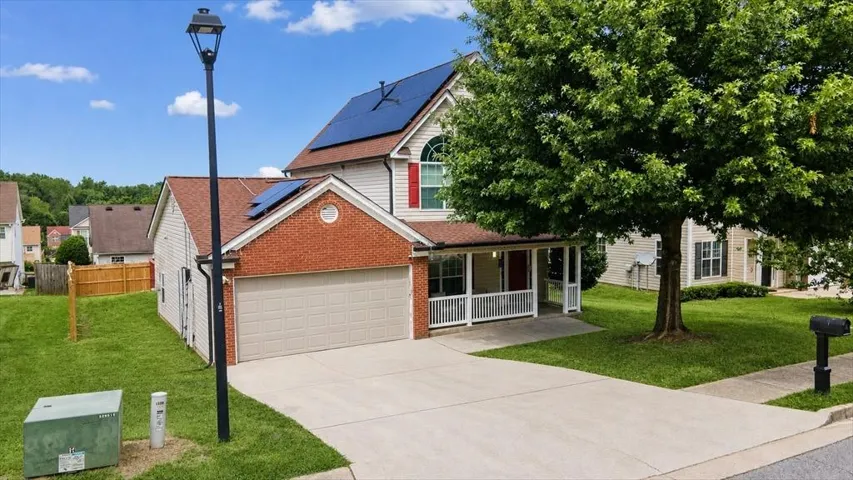 Siding exterior with brick accents, attached two-car garage, covered front porch, and solar panels