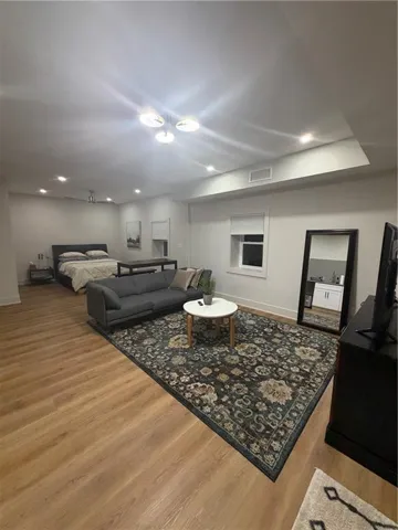 Recessed lighting, wood-finish flooring, a contemporary ceiling fixture, white walls, and white trim