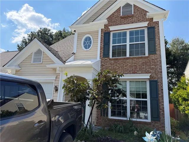 Brick and siding exterior with dark shutters, multiple gables, and an attached garage