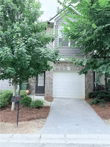 Two-story residential exterior featuring brick and horizontal siding, an attached garage with a white panel door, a black entry door, and a concrete driveway
