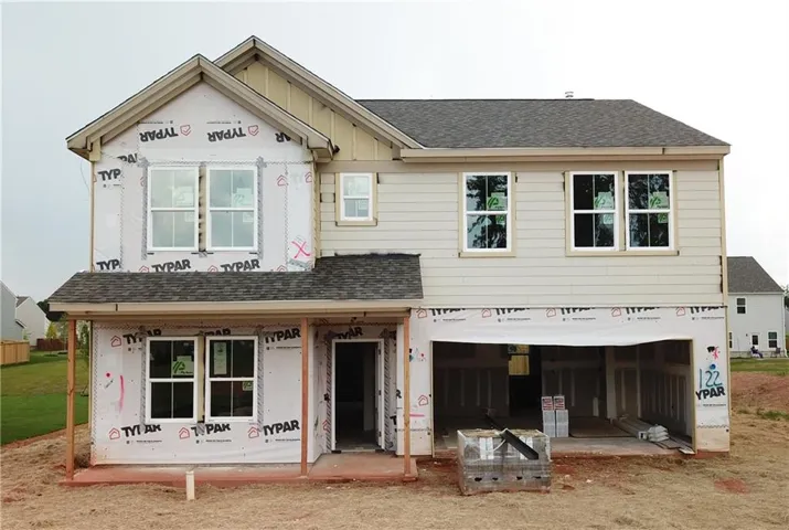Two-story residence featuring light-colored siding, a dark shingle roof, and multiple windows