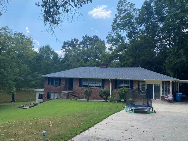 Brick exterior with a gray shingle roof and a covered carport