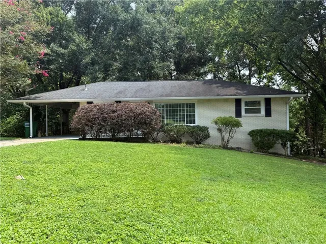 Single-story residence featuring light-colored brick siding, a dark shingle roof, and a covered carport