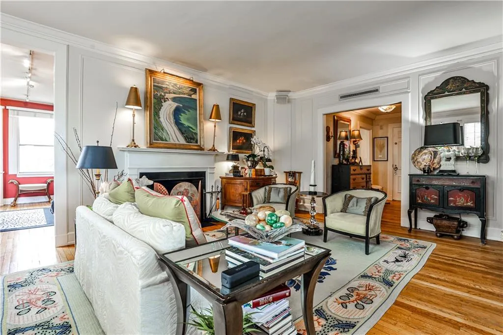 Living area with a decorative wall, wood finished floors, a fireplace, and ornamental molding