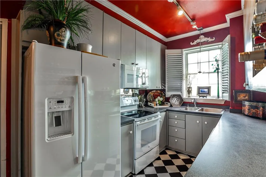 Kitchen with dark flooring, white appliances, dark countertops, gray cabinetry, and ornamental molding