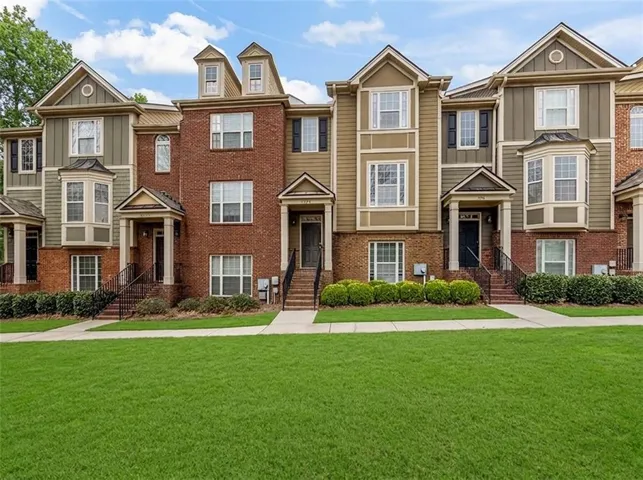 Townhome exterior featuring brick and siding facades, gabled roofs, decorative dormer windows, bay windows, and covered entryways