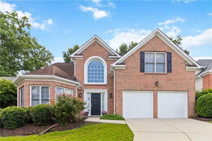 Brick Front exterior with a prominent arched window, a two-car garage, and a bay window