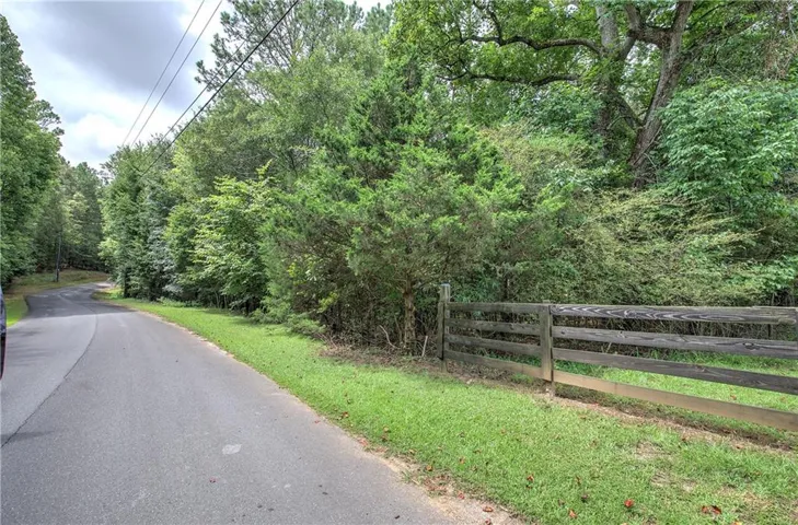 Over 1300 feet of paved road frontage, mature trees, lush greenery.
