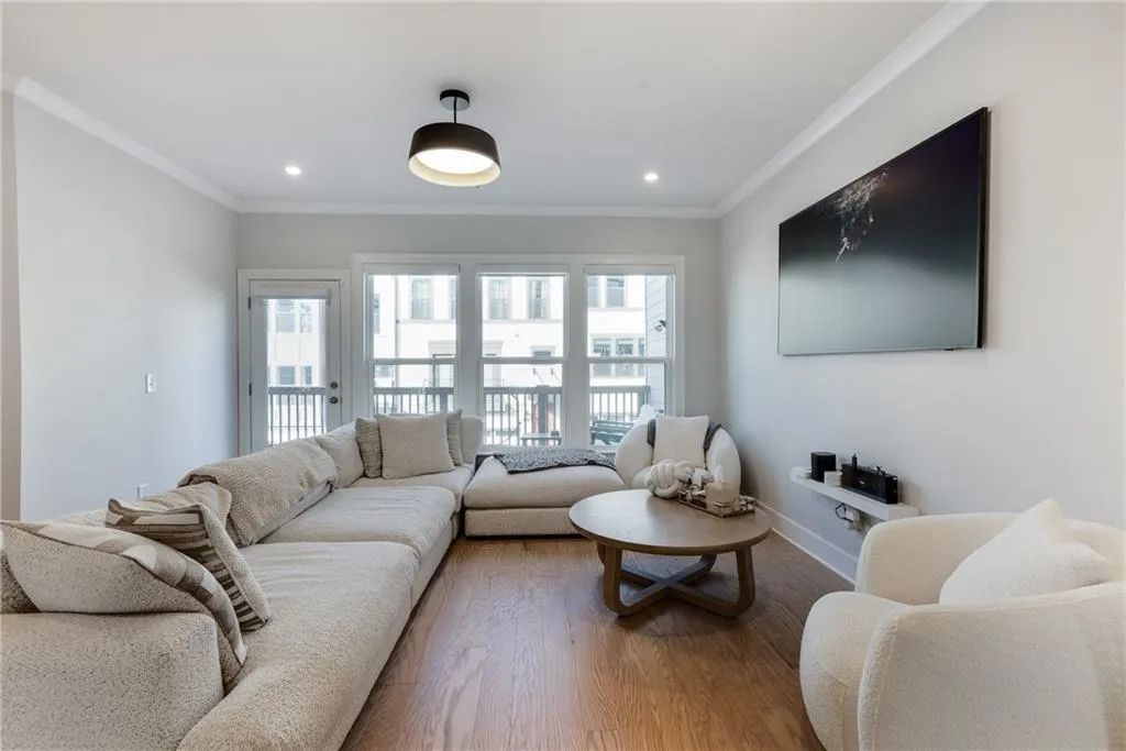Living area with healthy amount of natural light, crown molding, wood finished floors, and recessed lighting