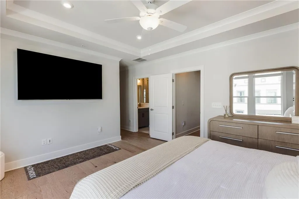 Bedroom featuring a tray ceiling, recessed lighting, wood finished floors, ceiling fan, and connected bathroom