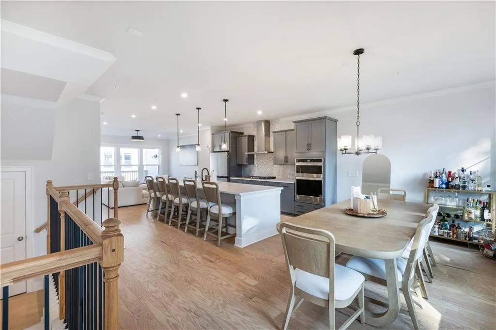 Kitchen with a center island with sink, backsplash, gray cabinets, ornamental molding, and light wood finished floors