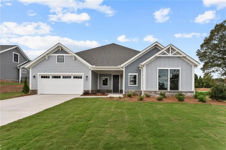 Craftsman-style home with board and batten siding, a front yard, concrete driveway, a garage, and covered porch