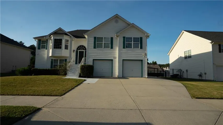 White siding exterior with a prominent bay window, arched entry, and dual garage doors