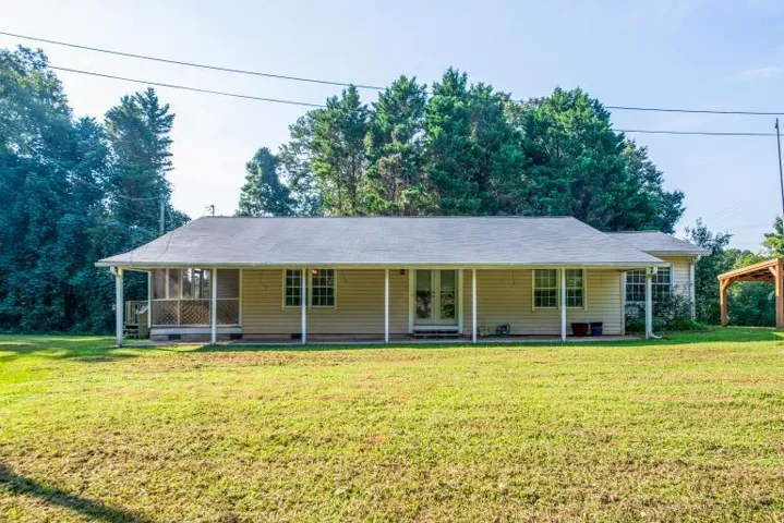 Charming ranch-style home situated on expansive grounds with mature tree line backdrop