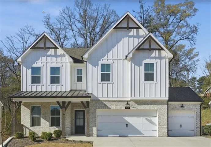 Modern farmhouse exterior with white board and batten siding, light-colored brick veneer, and exposed wood gables