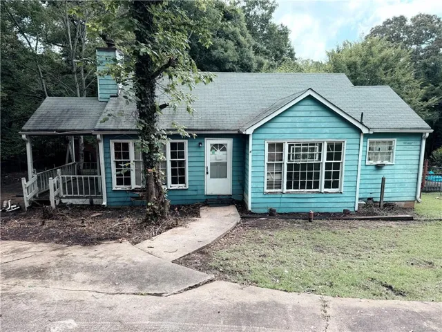 Single-story residence featuring a covered front porch, teal horizontal siding, and multiple multi-pane windows