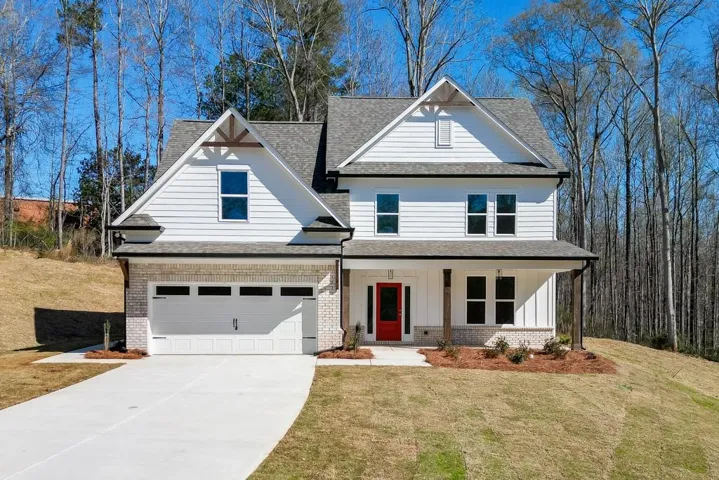 Contemporary craftsman-style residence featuring white siding, a contrasting dark roof, and a red entry door