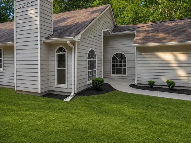 Siding exterior with arched windows, a prominent chimney, and a concrete pathway