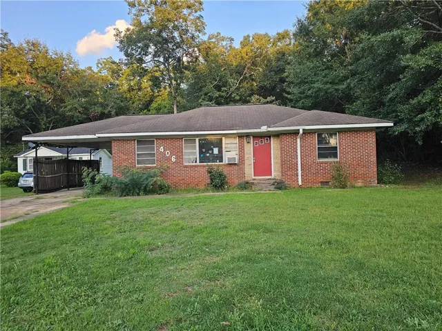 Brick exterior residence with a contrasting red entry door and a covered carport