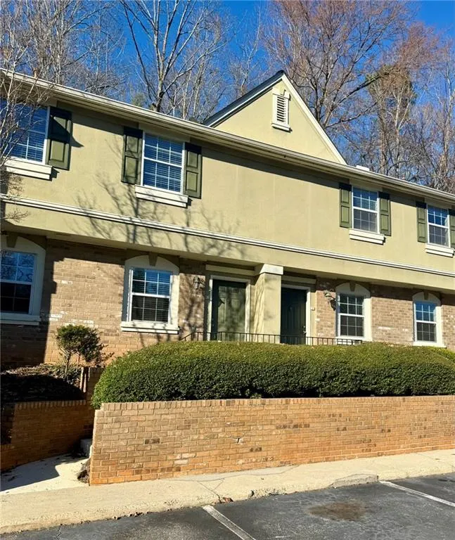 Colonial home with stucco siding, uncovered parking, and brick siding