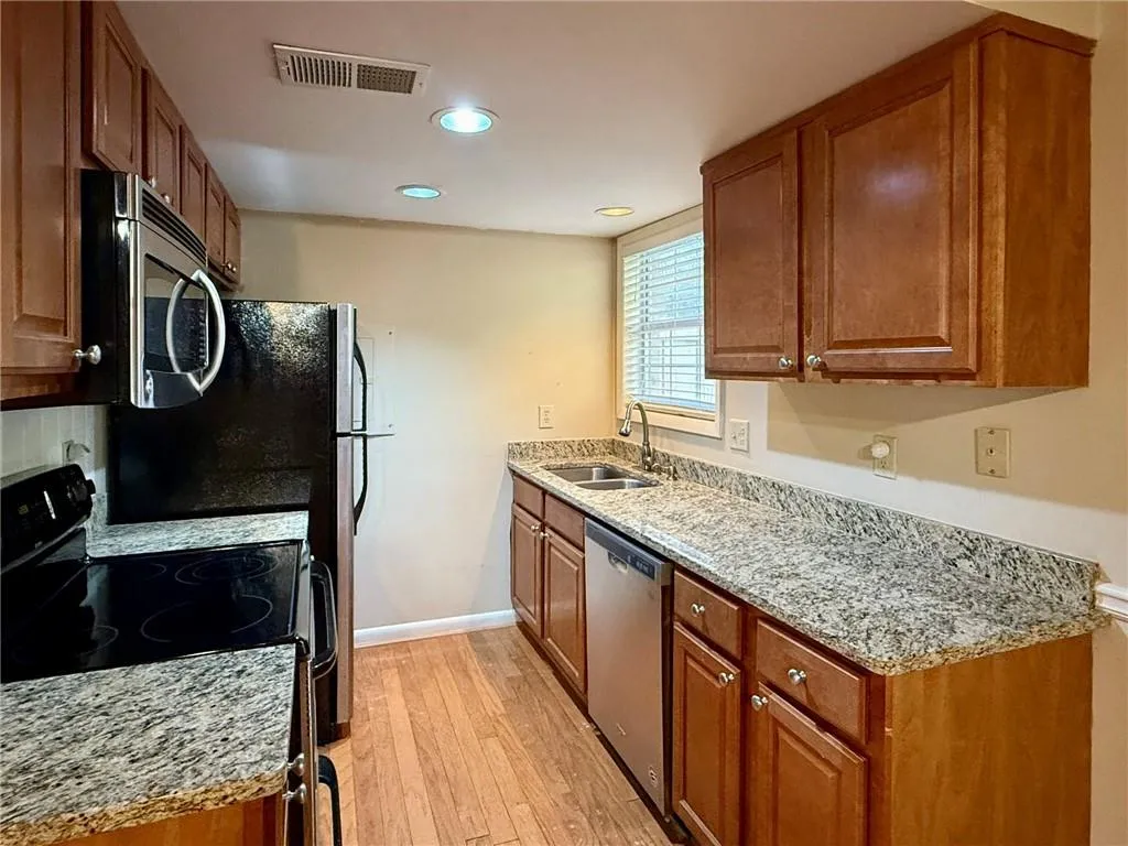 Kitchen with stainless steel appliances, brown cabinets, light wood-style flooring, and recessed lighting