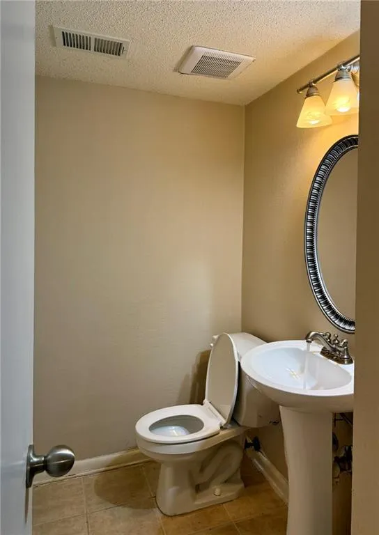 Half bath featuring a textured ceiling and light tile patterned flooring