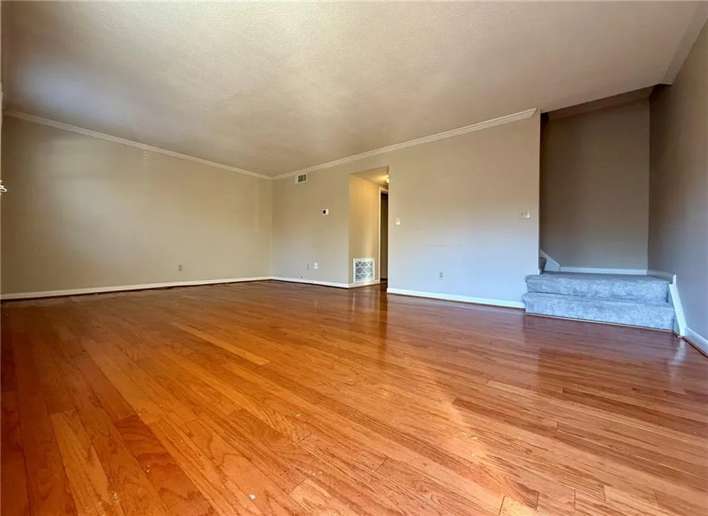 Unfurnished room featuring light wood-style floors, ornamental molding, and a textured ceiling