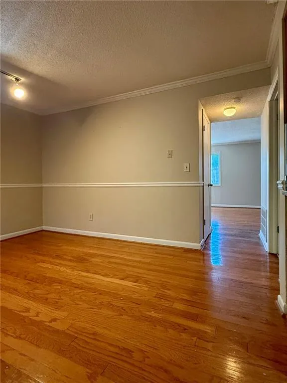 Spare room featuring a textured ceiling, light wood-style flooring, and crown molding