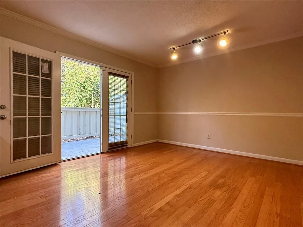 Spare room with light wood finished floors, crown molding, rail lighting, and a textured ceiling