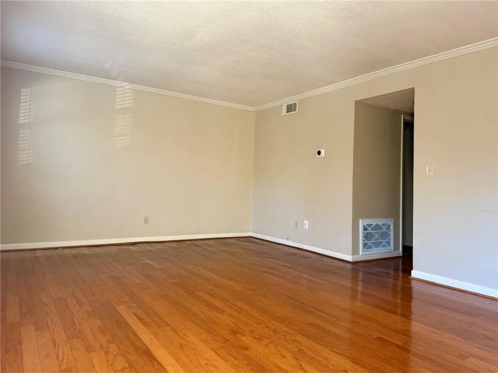 Spare room featuring hardwood / wood-style flooring, crown molding, and a textured ceiling