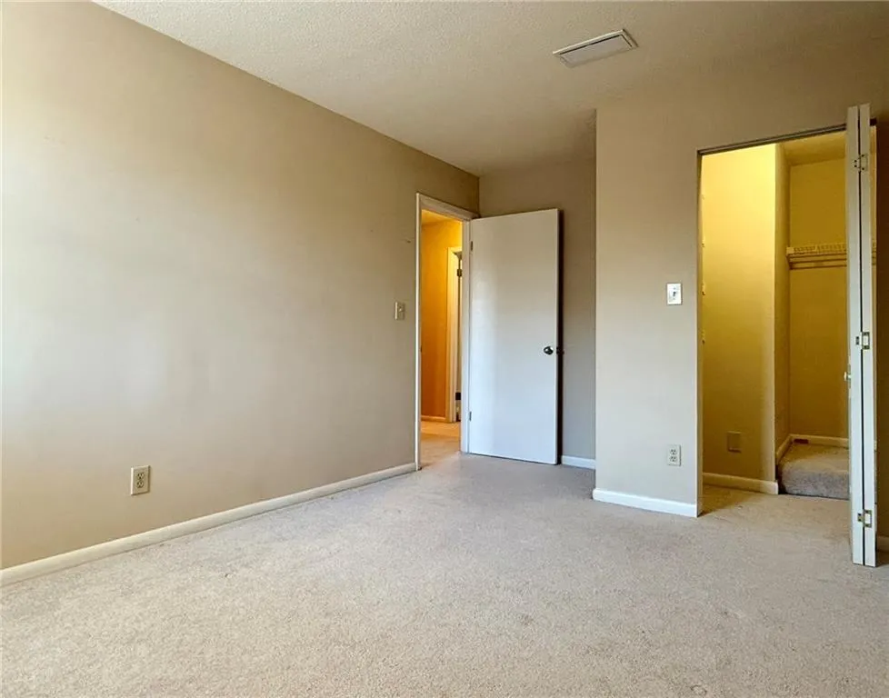 Unfurnished bedroom with carpet flooring, a walk in closet, and a textured ceiling