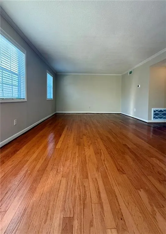 Spare room with hardwood / wood-style flooring, crown molding, and a textured ceiling