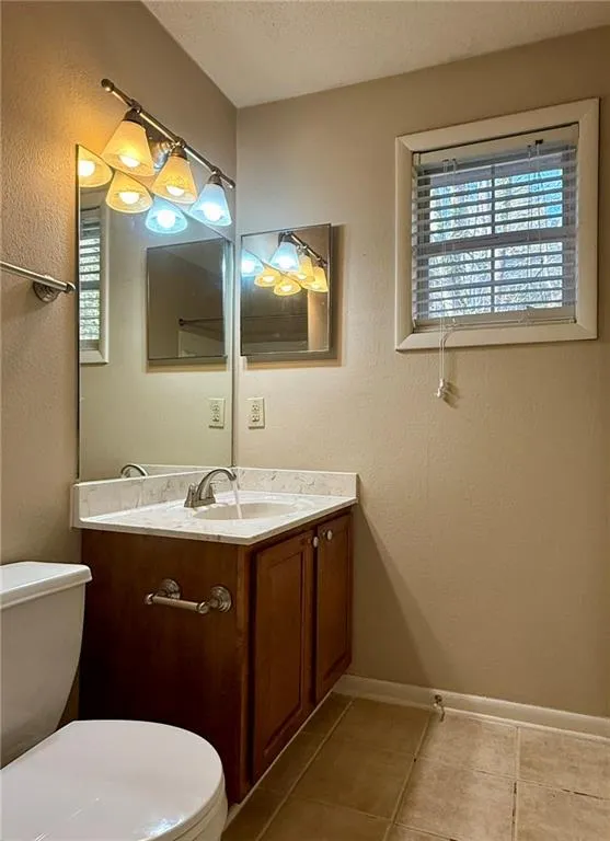 Half bath featuring plenty of natural light, vanity, a textured wall, a textured ceiling, and light tile patterned floors
