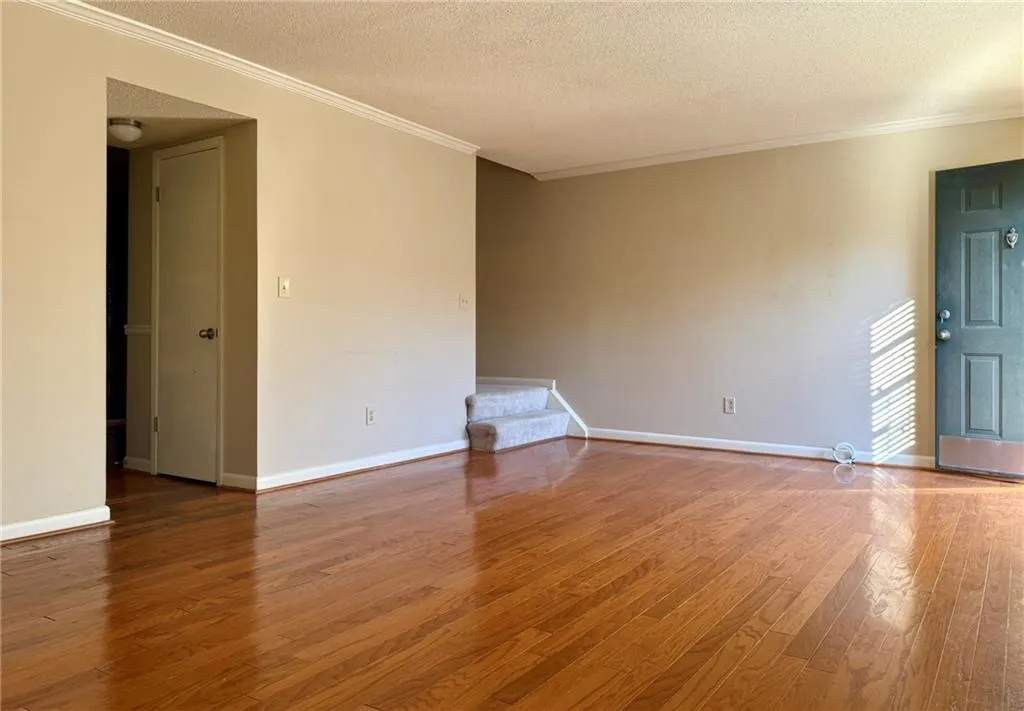 Unfurnished room with crown molding, light wood-type flooring, and a textured ceiling