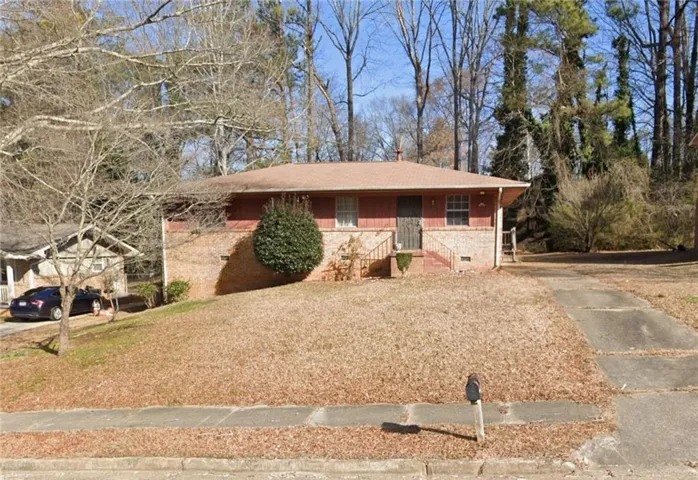 Charming brick ranch featuring a curved driveway and established landscaping