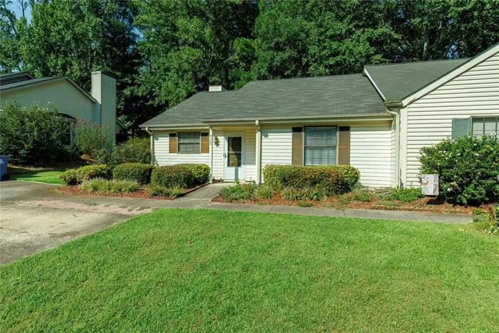 Exterior featuring light-colored siding, a dark shingle roof, and brown window shutters