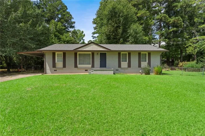 Brick exterior with an attached carport, front porch entry, and a spacious front lawn