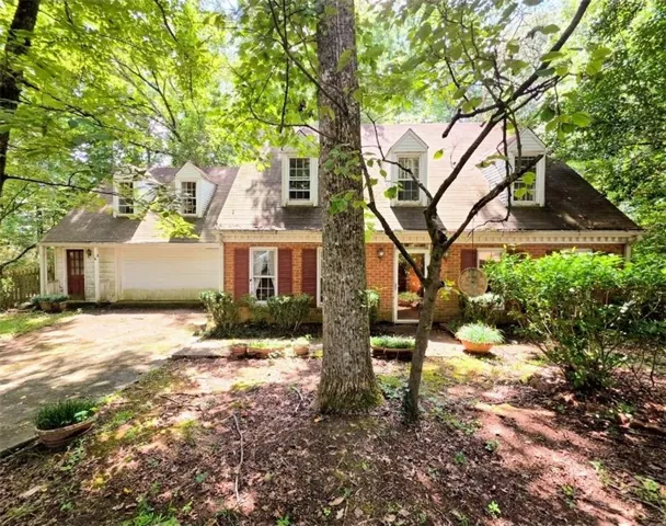 Brick facade with white trim, multiple dormer windows, red shutters, and an attached garage