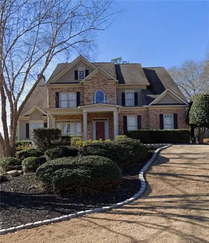 Brick and siding exterior featuring a covered front entry with columns, arched window, dark shutters, and a multi-gabled roofline