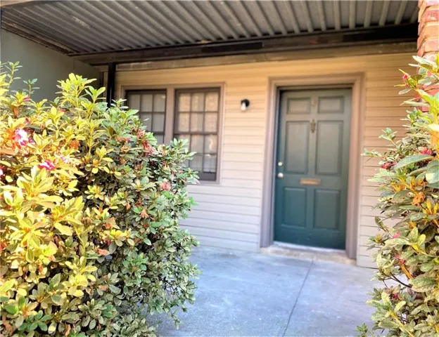 Entryway featuring a paneled green door, exterior wall lantern, and light-colored siding