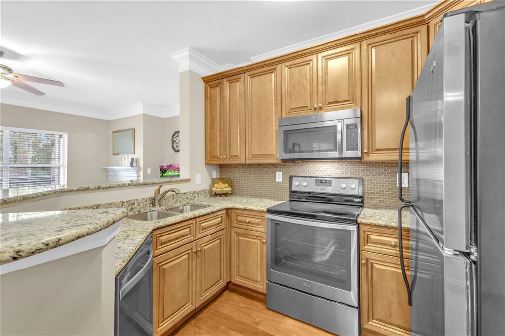Kitchen with light hardwood / wood-style flooring, backsplash, ceiling fan, sink, and stainless steel appliances