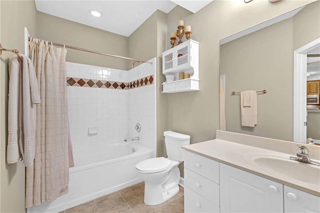 Second Full bathroom featuring tile floors, shower / bathtub combination with curtain, oversized vanity, and toilet