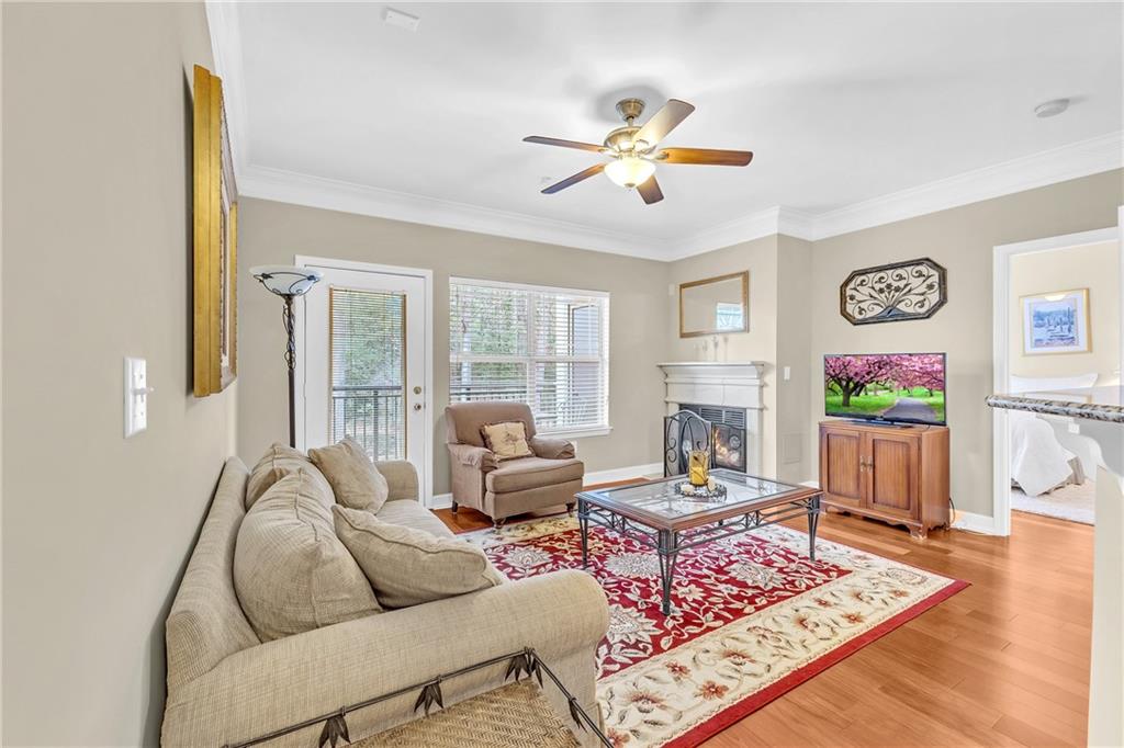 Living room with light hardwood / wood-style floors, crown molding, and ceiling fan