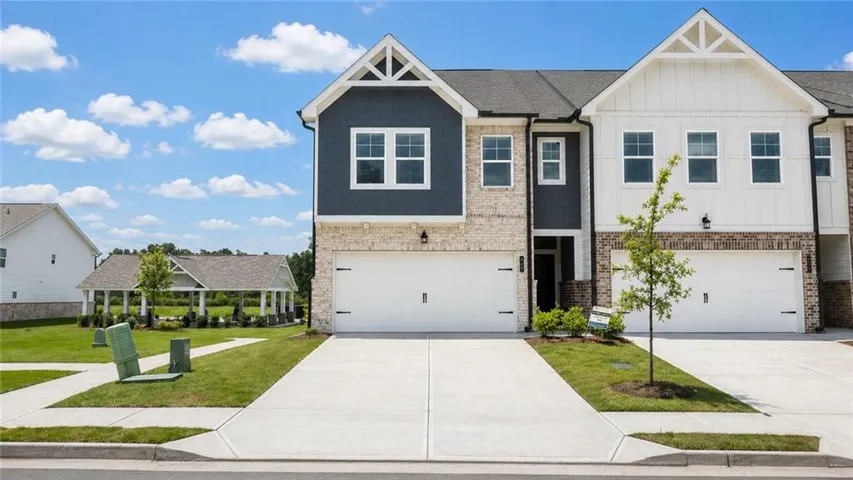 Contemporary townhome exterior with mixed material facade, featuring light-colored brick and dark blue siding