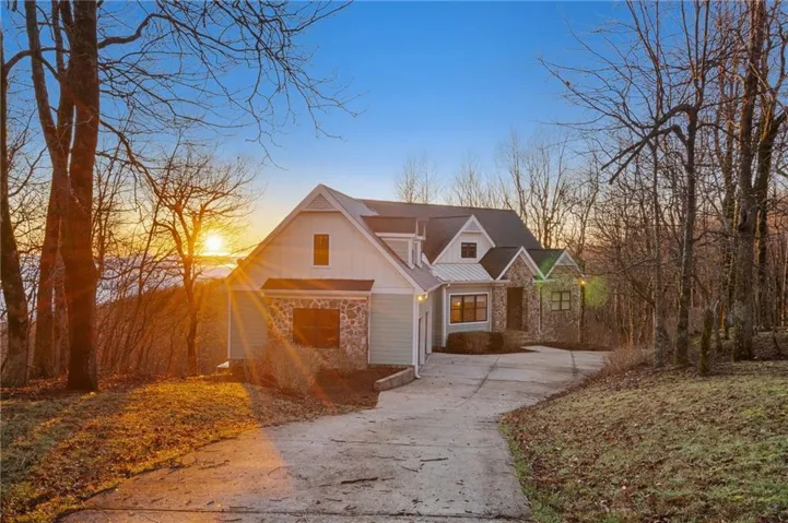 View of front of property featuring concrete driveway, a standing seam roof, board and batten siding, and stone siding