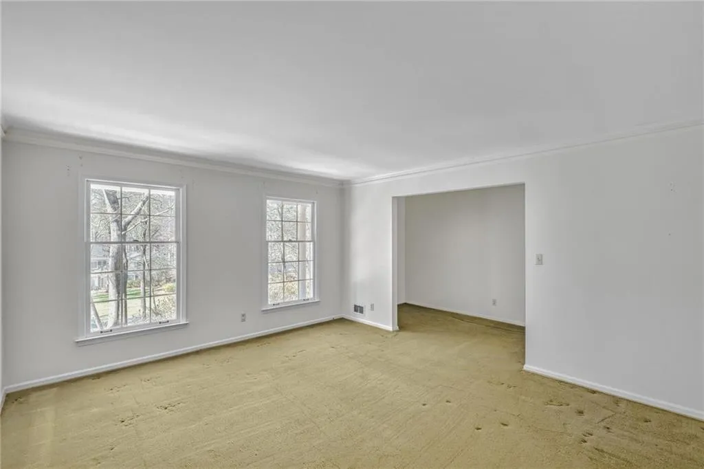 Spare room featuring baseboards, ornamental molding, and light colored carpet